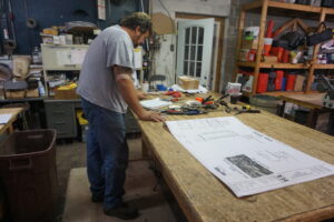 A man working on plans in his workshop.