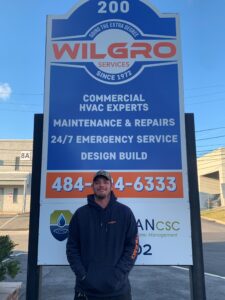 A man standing in front of a sign for wilgro