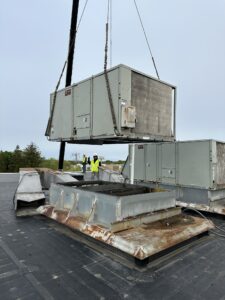 A large air conditioner being lifted off the roof.